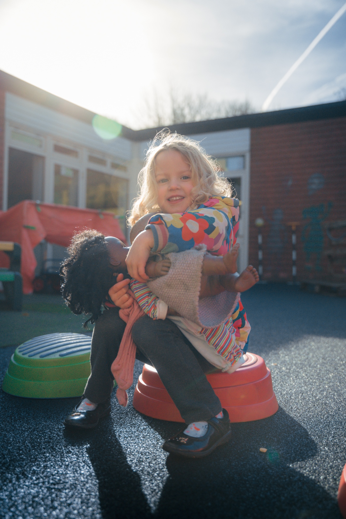 student smiling to camera with doll in playground