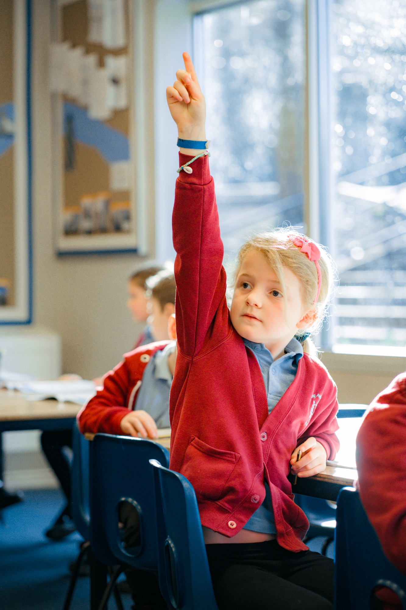 student with hand up in classroom