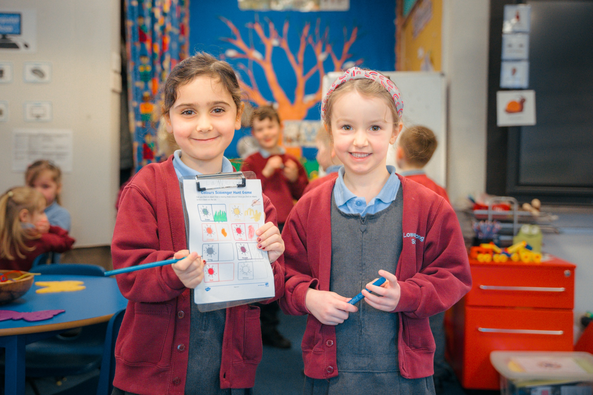 two students smiling and showing their work to camera