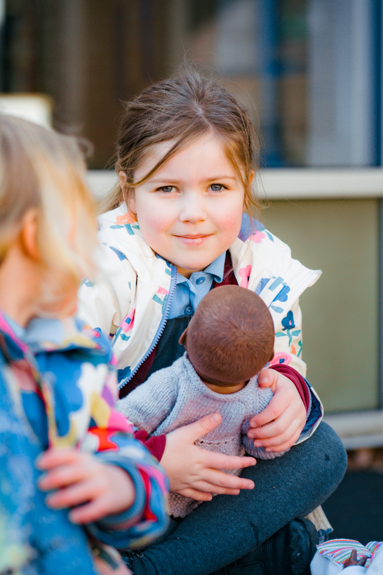 student holding doll looking at camera