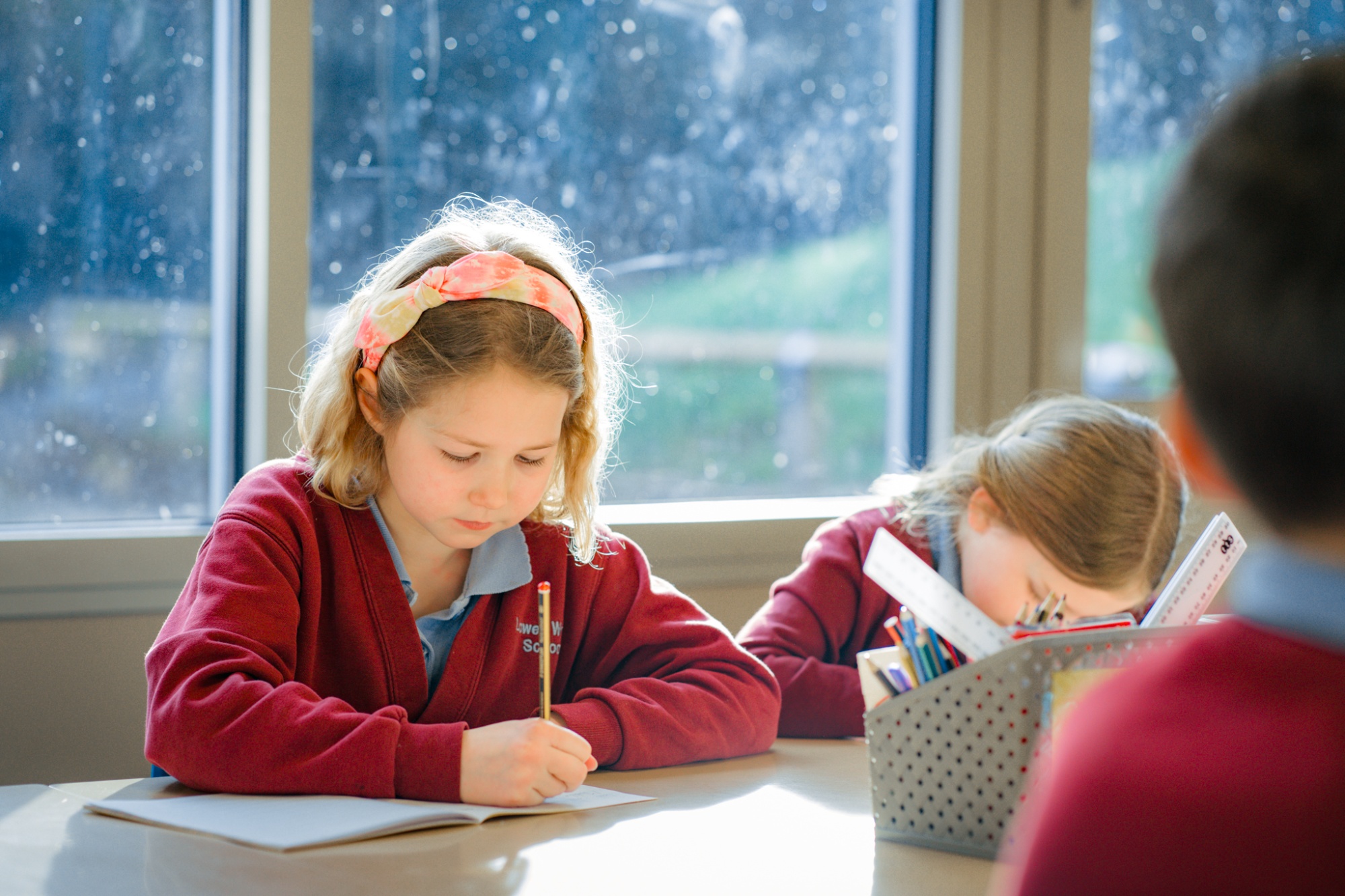 child writing in text book in class
