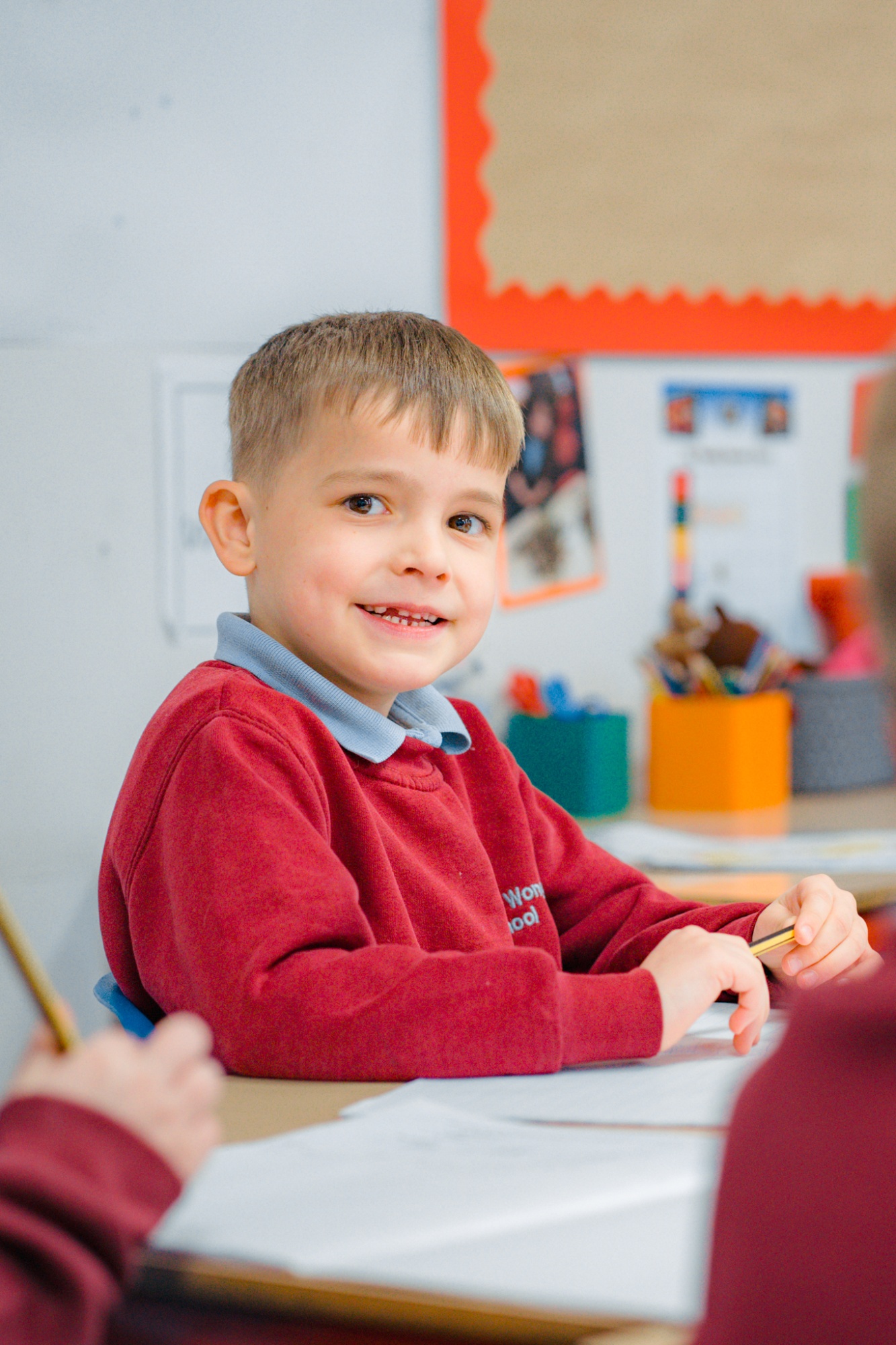 student at classroom table smiling to camera