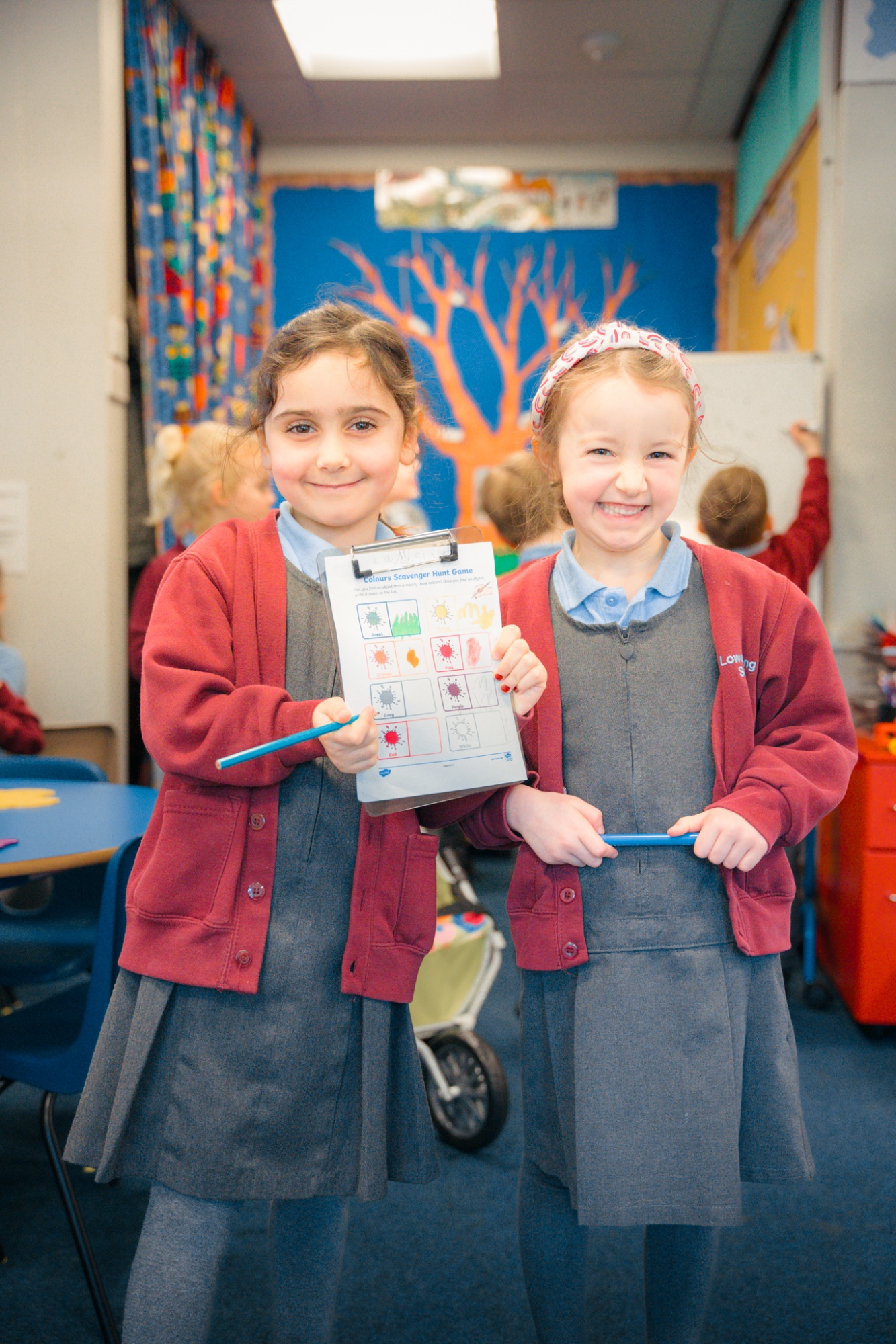 two children smiling and holding up their work to the camera