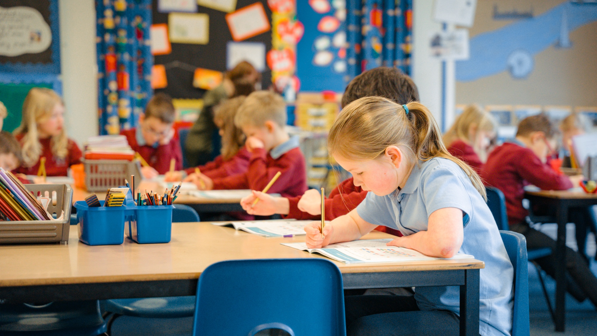 children working through text book in classroom
